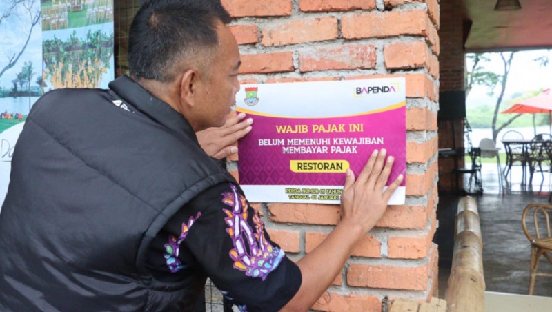 Petugas Bapenda Kabupaten Tangerang menempel stiker peringatan wajib pajak Restoran. (Foto: Dok Pemkab)